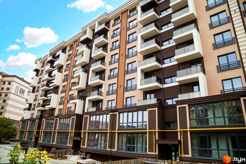 Зображення фасаду Житлового комплексу Modern з балконами та великими вікнами. На передньому плані видно квіти та частину прибудинкової території.