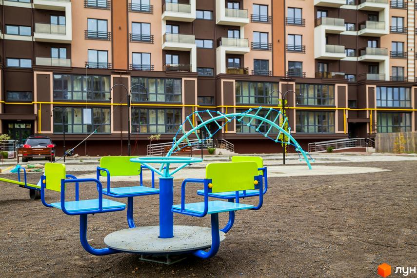 Зображення житлового комплексу Modern з дитячим майданчиком. Багатоповерховий будинок з великими вікнами та балконами.