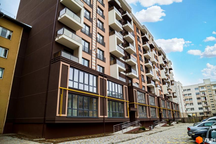 Зовнішній вигляд багатоквартирного будинку в Житловому комплексі Modern. Фасад будинку з балконами, поруч парковка для автомобілів.