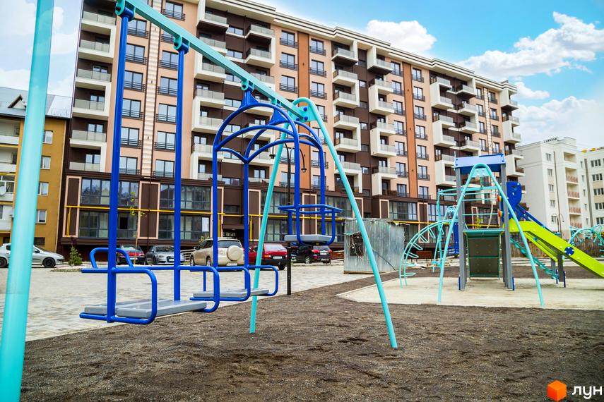 Зображення фасаду та дитячого майданчика Житлового комплексу Modern. Багатоповерховий будинок з балконами та ігровий простір для дітей.