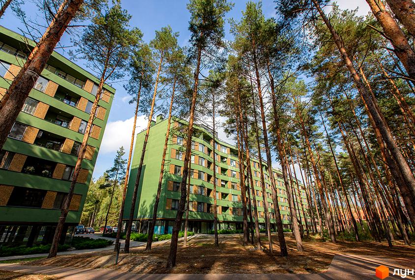 Зелений багатоповерховий будинок ЖК Park Town серед високих дерев. На території комплексу є доріжки та зелені насадження.