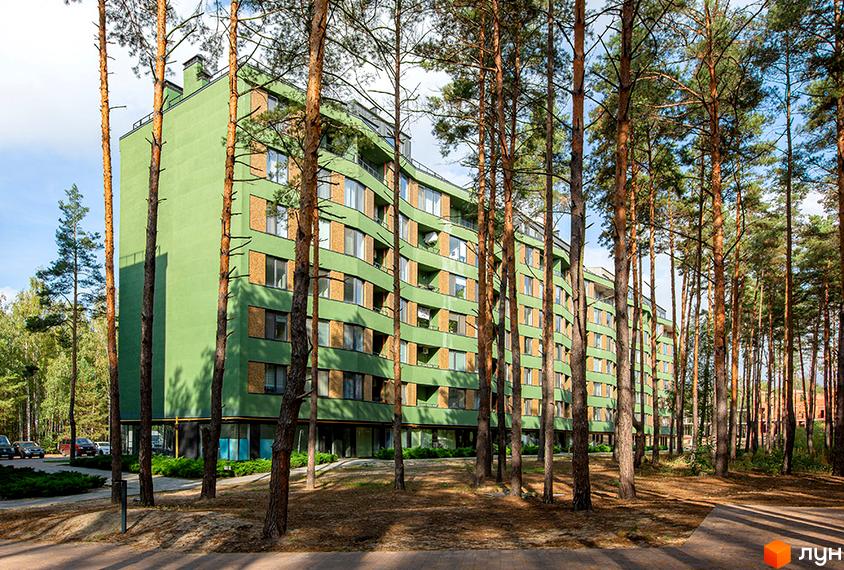 Зелений багатоповерховий будинок ЖК Park Town серед соснового лісу. Навколо будівлі доглянута прибудинкова територія з деревами та кущами.