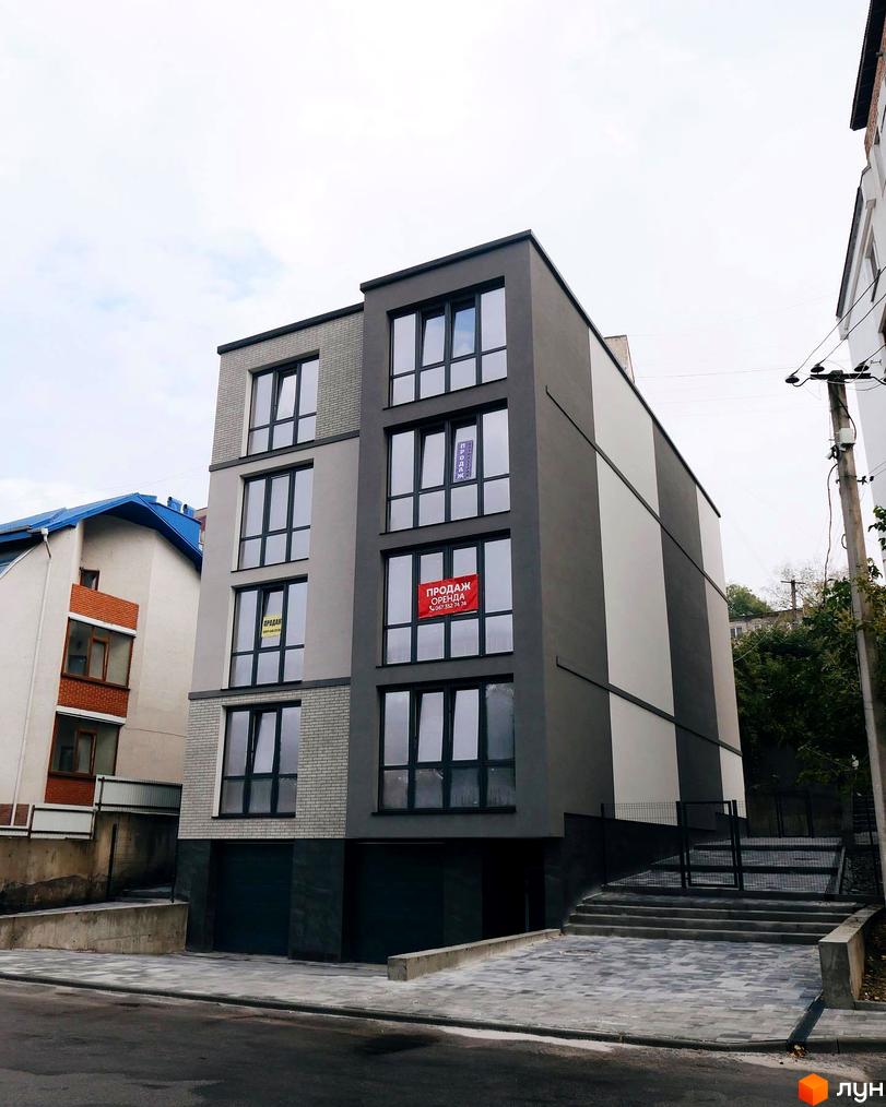 Клубний будинок „Над Ставом“ з сірим фасадом та великими вікнами, поруч сходи та тротуар.