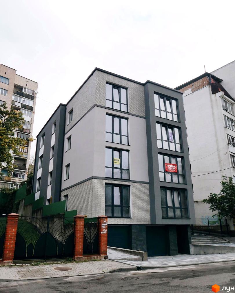 Клубний будинок „Над Ставом“ з сірою та білою цегляною фасадною обробкою, великими вікнами та зеленими воротами з кованими елементами.