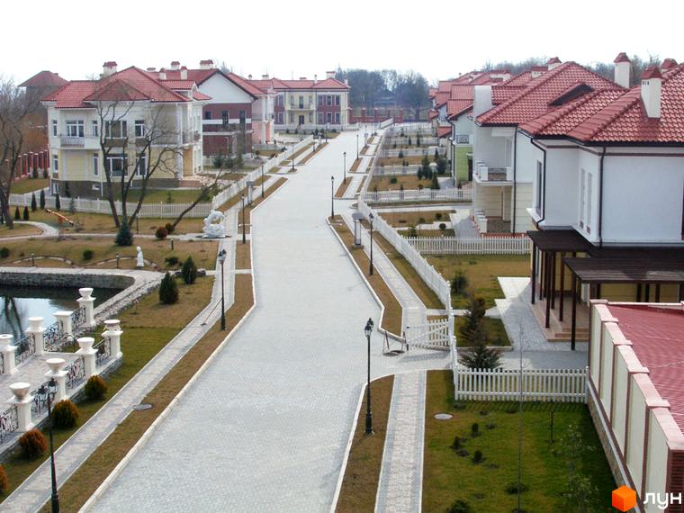 Зображення Котеджного містечка Аріадна. Вигляд на вулицю з котеджами та доглянутою територією з газонами і декоративними рослинами.