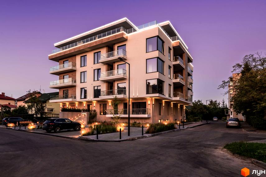 Житловий комплекс Baltiysʹka Hall з освітленим фасадом та скляними балконами. На прибудинковій території видно доріжки, озеленення та автомобілі.