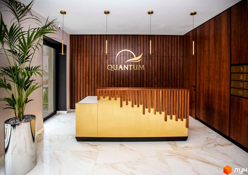 Інтер'єр лобі Житлового комплексу Baltiysʹka Hall з дерев'яними стіновими панелями, золотистою стійкою реєстрації та логотипом. Підлога з білого мармуру.