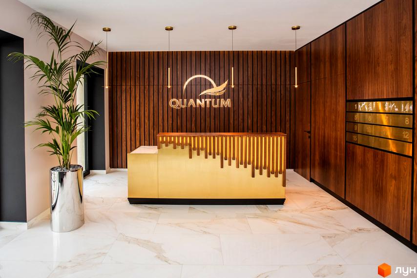 Лобі Житлового комплексу Baltiysʹka Hall: золотиста стійка реєстрації з підсвіткою, стіна з дерев'яних панелей, поштові скриньки та рослина.