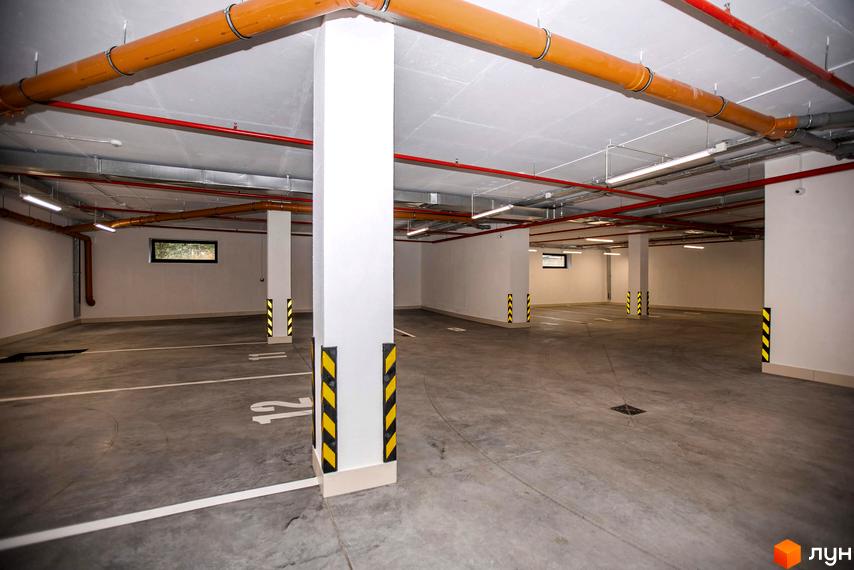 Підземний паркінг Житлового комплексу Baltiysʹka Hall з розміткою для паркування та яскравим освітленням.