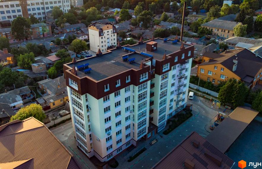 Зовнішній вигляд багатоповерхового будинку житлового комплексу на вулиці Монастирській, 4г. На прибудинковій території видно дитячий майданчик та місця для відпочинку.