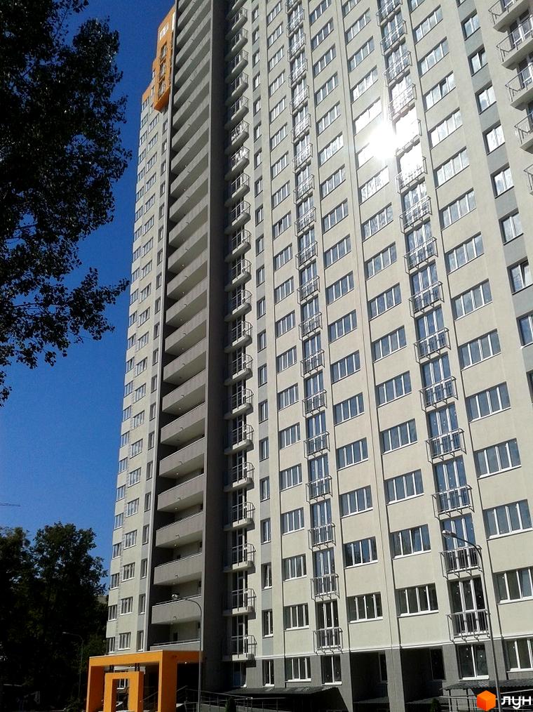 Зображення фасаду багатоповерхового будинку в Житловому комплексі Лідер. Вигляд новобудови з великою кількістю вікон та балконів.