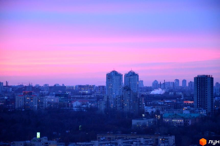 Панорамне фото Житлового комплексу Лідер на фоні рожевого неба. Вид на багатоповерхівки та міську забудову в сутінках.