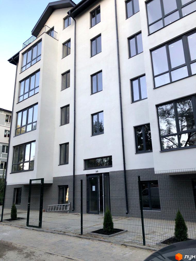 Клубний будинок «Зразковий» з великими панорамними вікнами та сітчастим парканом навколо території. На прибудинковій території висаджені туї та облаштований прохід.