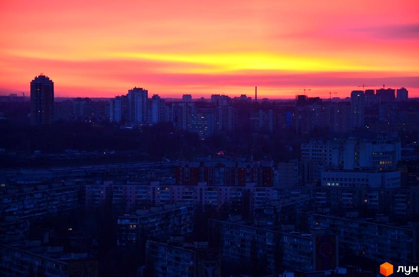 Фото панорами міста з Житловим комплексом Лідер на фоні яскравого заходу сонця. Вид на багатоповерхівки та міську забудову.