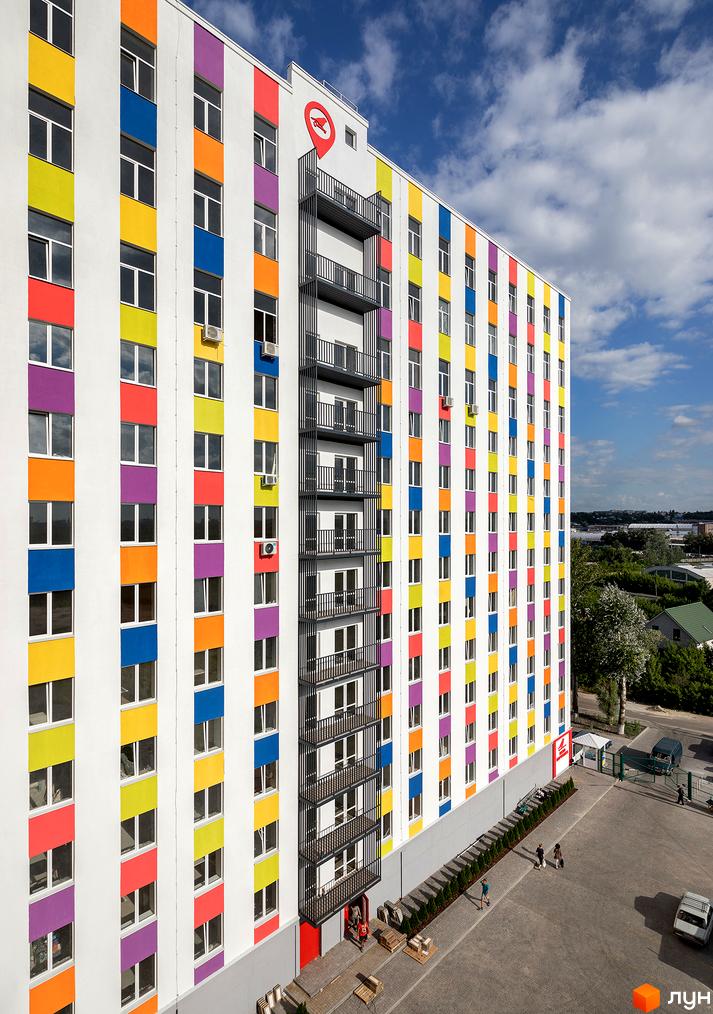 Житловий комплекс Воробйовi гори з яскравим фасадом та кольоровими смугами. На території комплексу є парковка та зелені насадження.