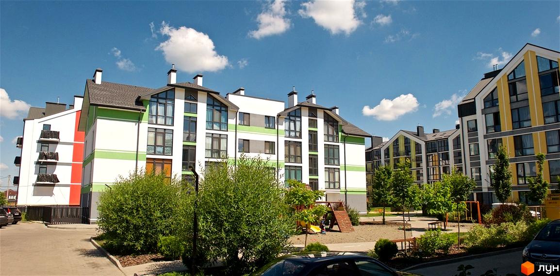 Житловий комплекс Петрівське містечко: фасади будинків з панорамними вікнами та зелені насадження на прибудинковій території.