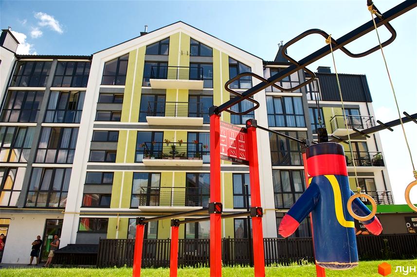 Житловий комплекс Петрівське містечко: багатоповерховий будинок з яскравим фасадом та спортивним майданчиком на прибудинковій території.