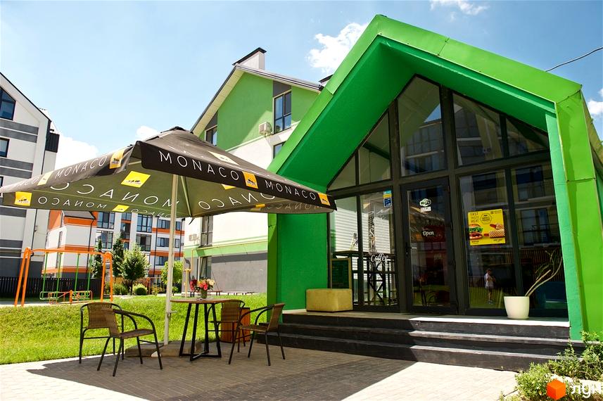 Зовнішній вигляд комерційного приміщення з терасою в ЖК Петрівське містечко. Тераса облаштована парасолькою та вуличними меблями.