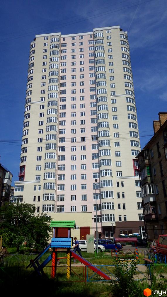 Житловий комплекс Будинок на Клименка: багатоповерховий будинок світлих відтінків з численними вікнами. На передньому плані дитячий майданчик.