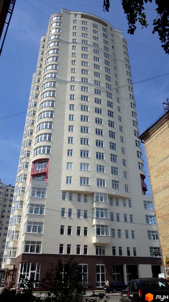 Житловий комплекс Будинок на Клименка: висотна будівля світлого кольору з численними вікнами та балконами. На передньому плані видно дерева та припарковані автомобілі.