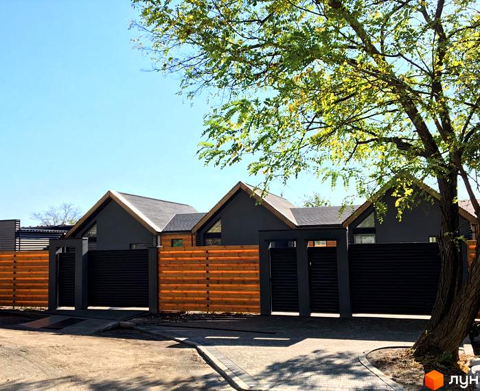 Зовнішній вигляд будинків житлового комплексу на вул. Євпаторійська, 108, з сучасним фасадом та огородженою територією з дерев'яним парканом та воротами.