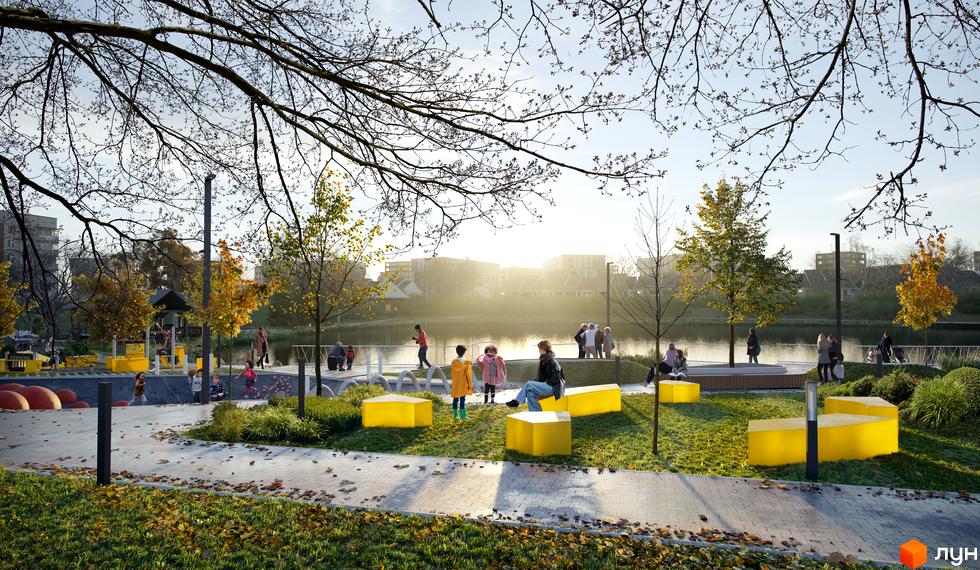 Житловий комплекс Pictorial: зелена зона з дитячим майданчиком біля водойми, сучасні жовті лавки та дерева з осіннім листям.