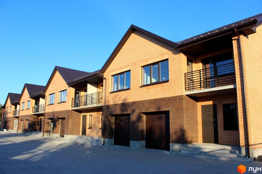 Ряд таунхаусів WestSide з цегляним фасадом та темними дахами. Перед будинками вимощена територія.