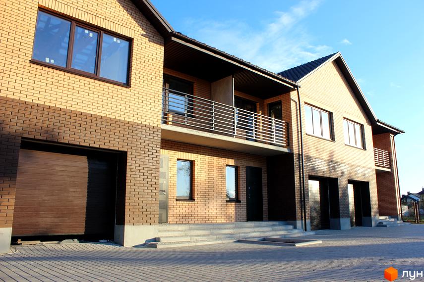 Таунхауси WestSide з цегляним фасадом світлого та темно-коричневого кольорів, балконами та гаражами. Прибудинкова територія вимощена бруківкою.