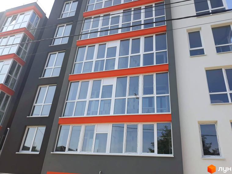 Зовнішній вигляд Житлового комплексу Микулинецька-Кемпінг: багатоквартирний будинок з темно-сірим та світлим фасадами, вікнами та заскленими балконами.