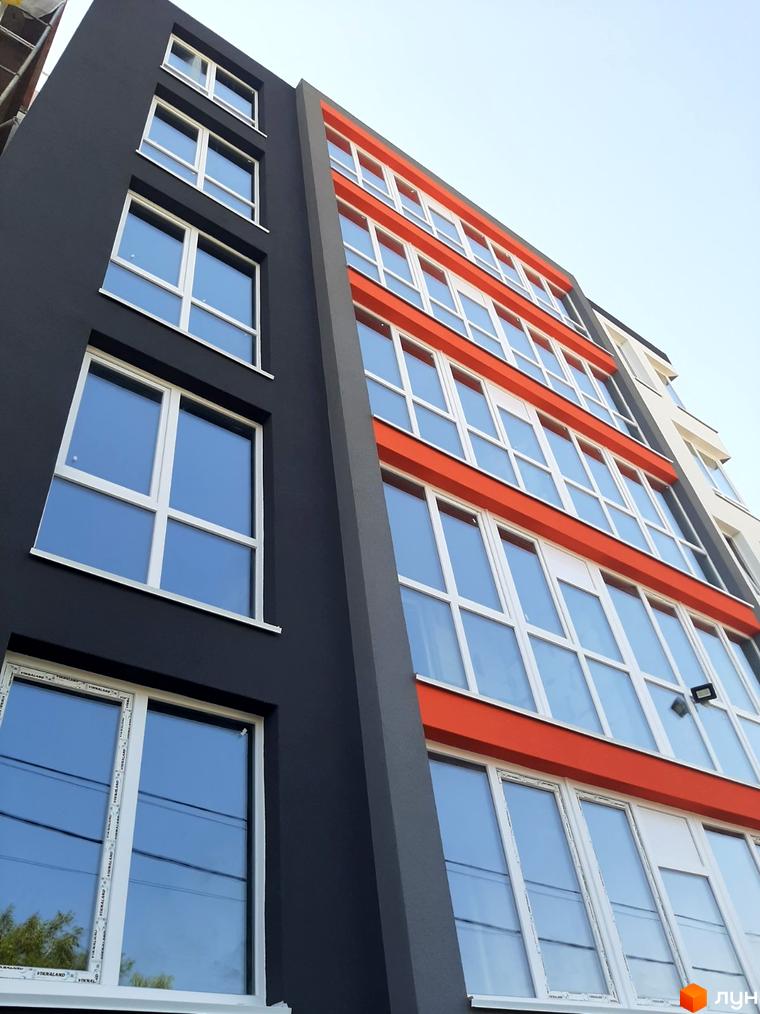 Житловий комплекс Микулинецька-Кемпінг: багатоповерховий будинок з темно-сірим фасадом та яскравими помаранчевими вставками.