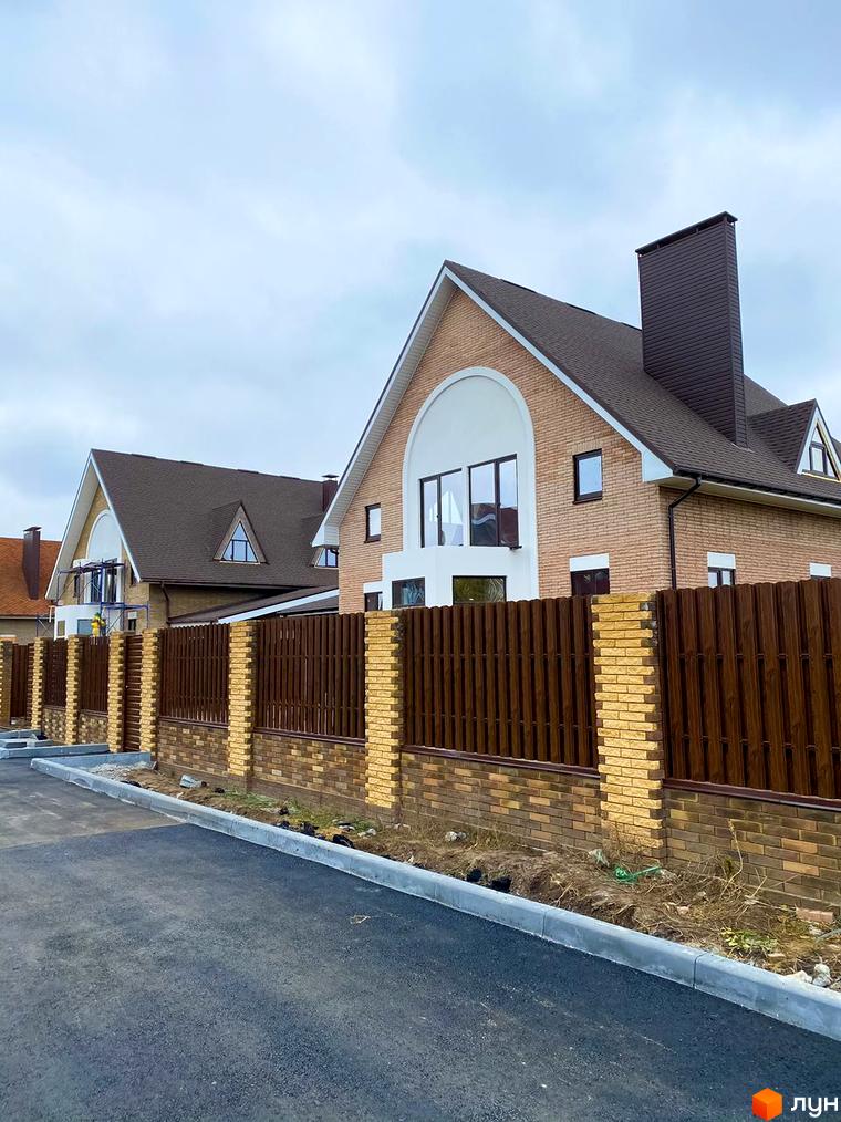 Котеджне містечко КМ Барвіта: двоповерхові цегляні будинки з коричневим дахом та парканом. Прибудинкова територія з асфальтованою дорогою та бордюром.