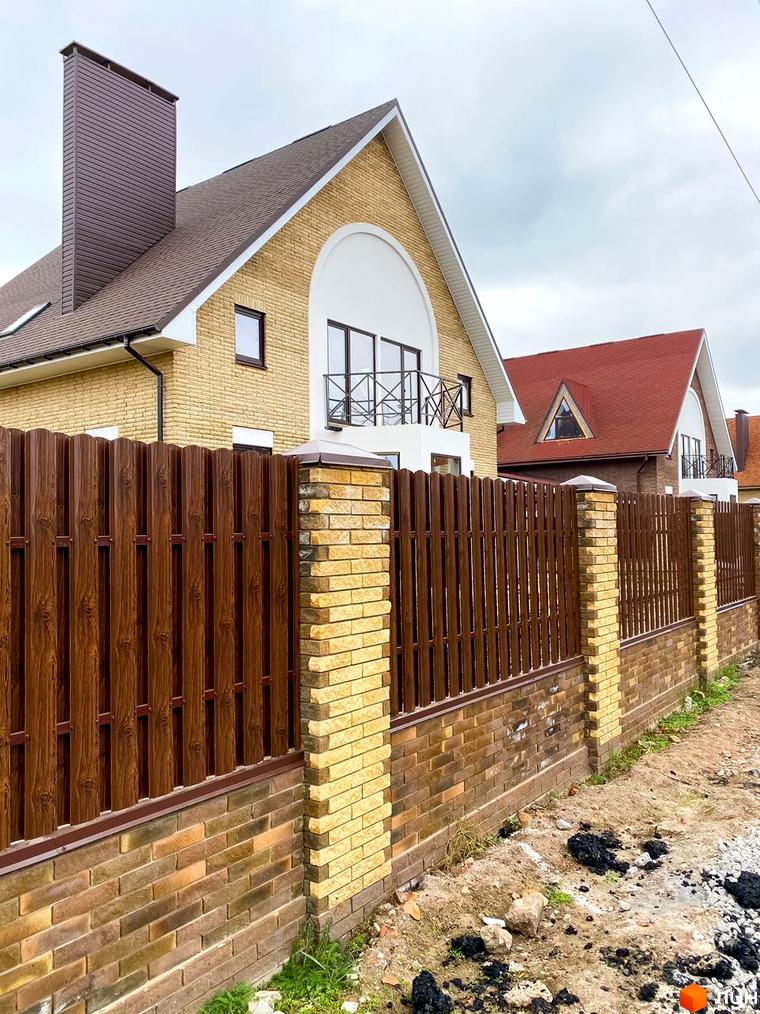 Котеджне містечко КМ Барвіта: цегляний будинок з коричневим парканом та черепичним дахом. Прибудинкова територія з елементами ландшафтного дизайну.