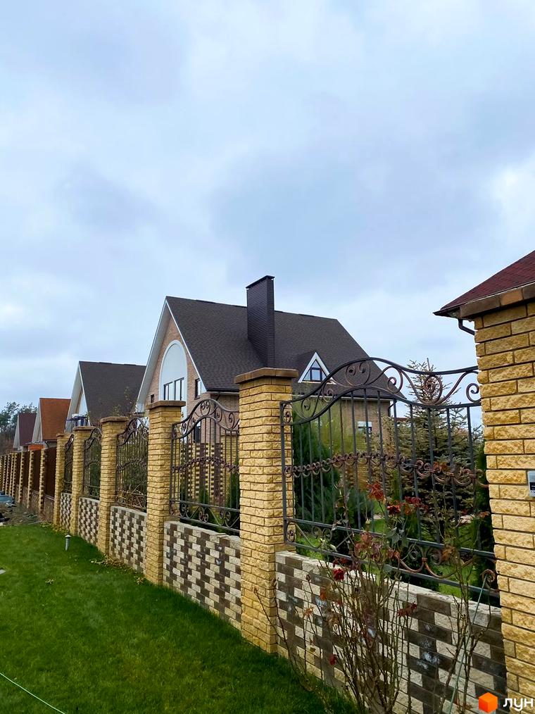 Котеджне містечко КМ Барвіта: фасади будинків з цегли та ковані огорожі на тлі зеленої галявини.