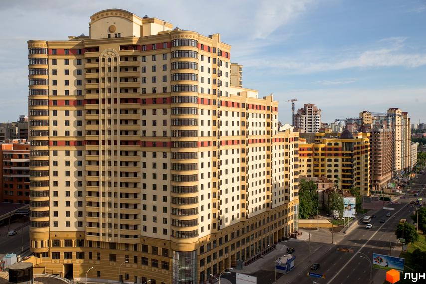 Житловий комплекс Златоустівський з фасадом в світлих тонах та балконами. Прибудинкова територія з проїзною частиною та зеленими насадженнями.