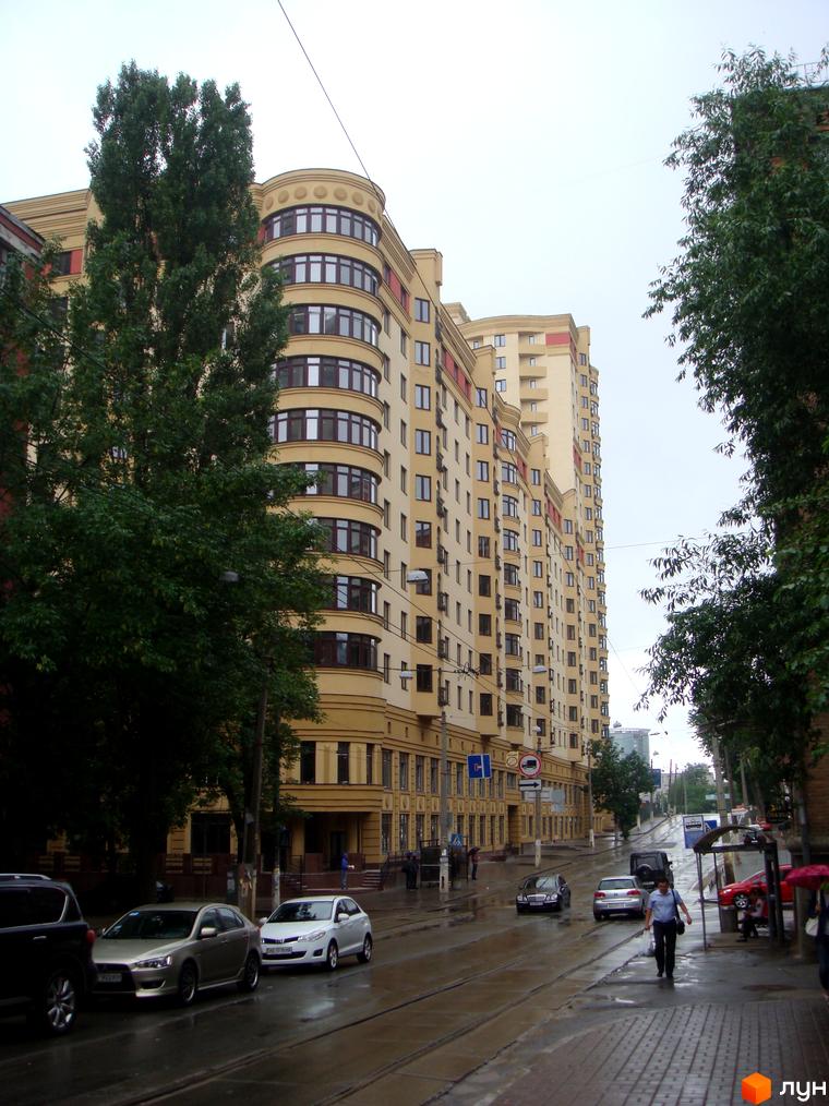 Житловий комплекс Златоустівський з виглядом на фасад та прибудинкову територію, де паркуються автомобілі.