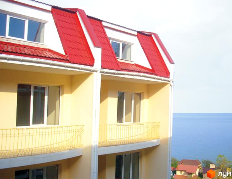 Будинок житлового комплексу Park-House з червоною покрівлею та балконами. Прибудинкова територія з видом на водойму.