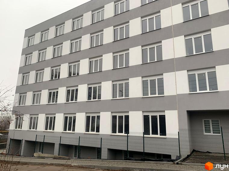 Фасад житлового комплексу Муромець з сіро-білими смугами та численними вікнами. На передньому плані видно огорожу та ділянку біля будинку.