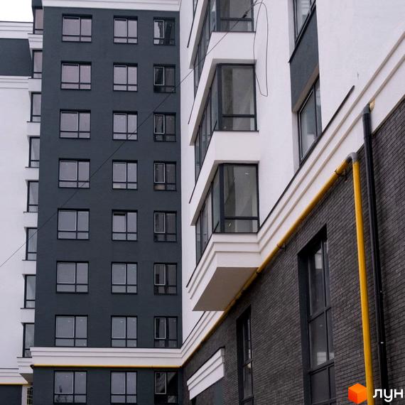 Фасад Житлового комплексу Олімп: багатоповерхові будинки з комбінованим оздобленням у білому та темно-сірому кольорах, з великими вікнами та зовнішніми комунікаціями.