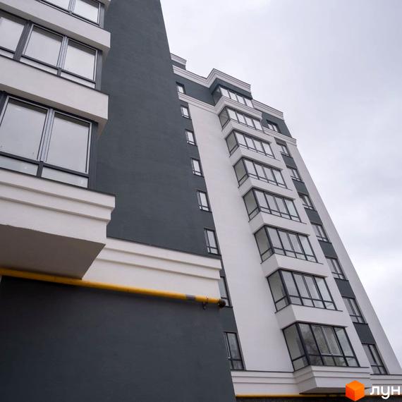 Багатоповерховий будинок Житлового комплексу Олімп з білими та темно-сірими фасадами, великими вікнами та заскленими балконами.
