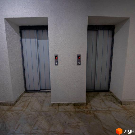 Ліфтовий хол Житлового комплексу Олімп: два ліфти з металевими дверима, світлі стіни та плитка на підлозі.