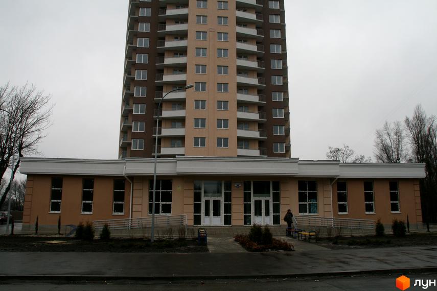 Житловий комплекс на вул. Ушинського, 14б, з сучасним фасадом та прибудинковою територією. Вид на вхідну групу та парковку.