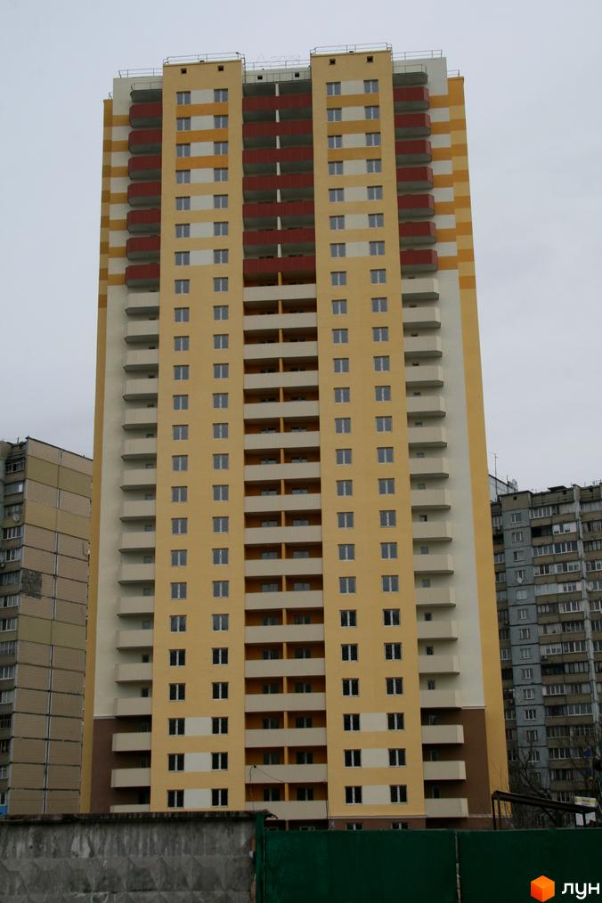 Фасад новобудови на вулиці Хорольській, 1а, у Києві. Багатоповерховий будинок з балконами та вікнами, виконаний у жовто-білих кольорах.