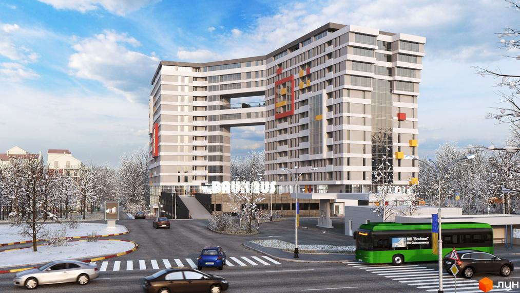 Житловий комплекс Bauhaus – це багатоповерховий будинок з незвичайним архітектурним рішенням та кольоровими акцентами. Навколо новобудови розташовані дерева, вкриті снігом, та проїжджа частина з автомобілями.