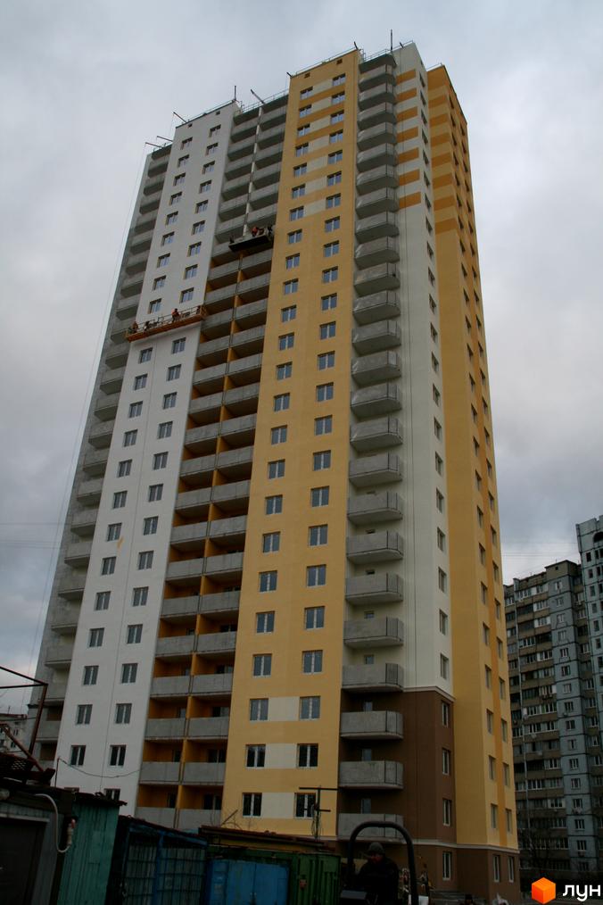 Будівельний проєкт на вул. Хорольська, 1а. Висотна новобудова з жовто-білим фасадом та балконами, що будується на фоні хмарного неба.