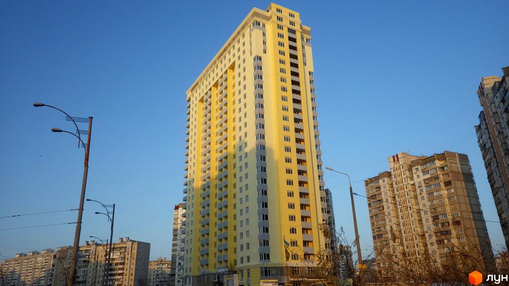 Високий житловий будинок жовтого кольору з численними балконами та вікнами на вулиці Радунській, 28-32. Навколо видно інші будівлі та елементи міського пейзажу.
