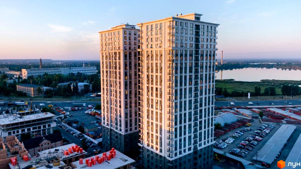 Новобудова ЖК Метрополія з двома вежами, що височіють над містом. Навколо новобудови розташовані дороги з автомобілями та парковка.