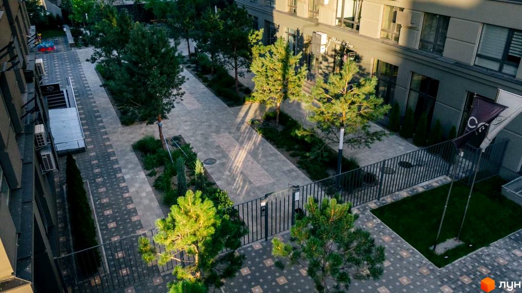 Житловий комплекс Метрополія. Зовнішній вигляд будівель та облаштована прибудинкова територія з зеленими насадженнями та пішохідними доріжками.