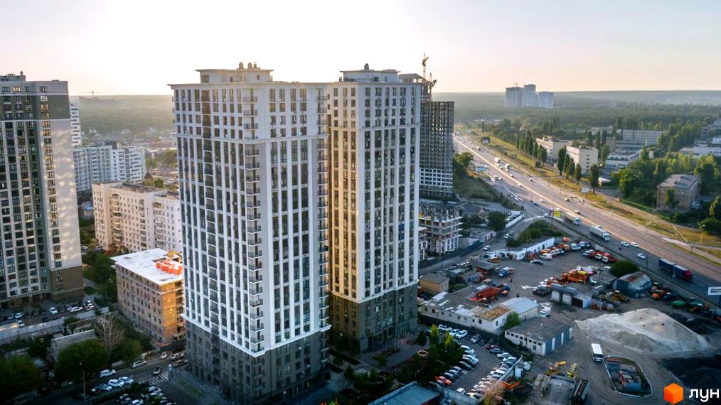 Житловий комплекс Метрополія - сучасна архітектура та міська інфраструктура. Вид на висотні будинки та прилеглу територію з автомобілями та дорогою.