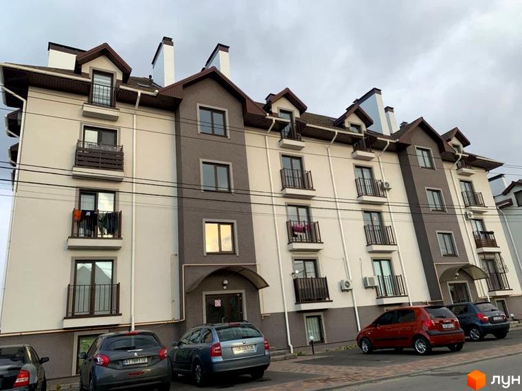 Житловий комплекс Петрівський. Фасад новобудови з балконами та вікнами, парковка з автомобілями.