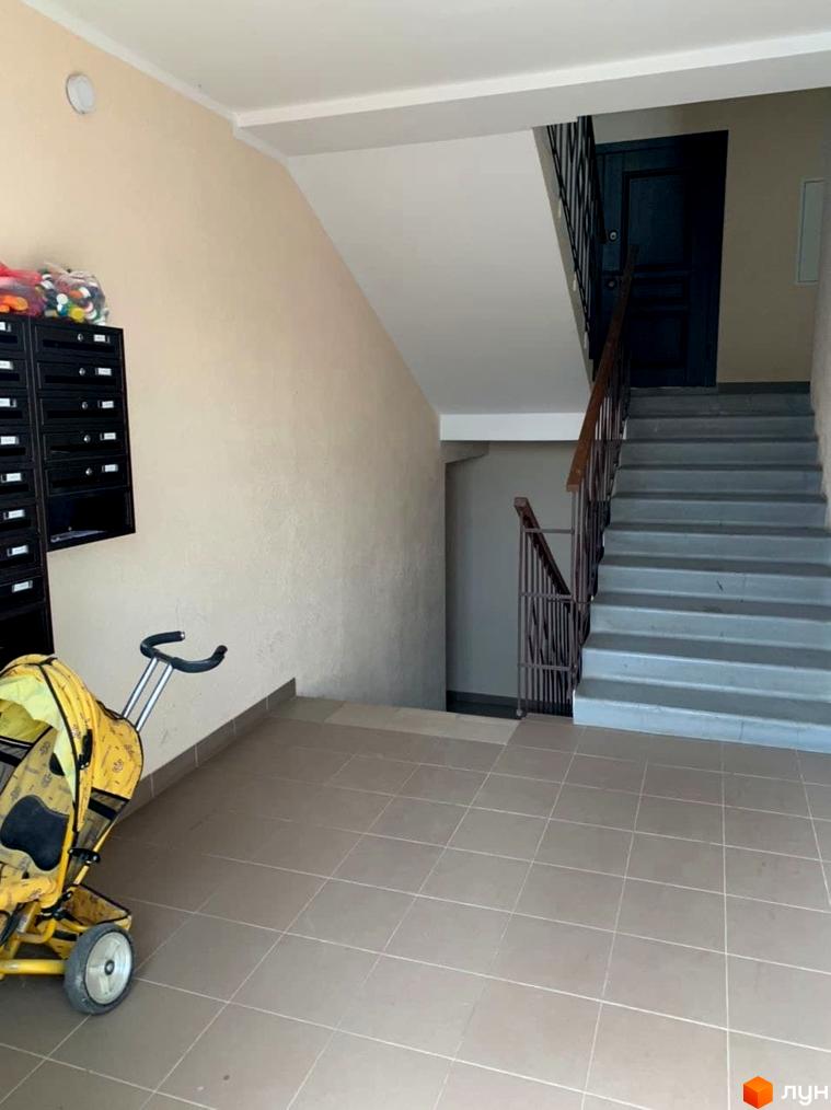 Вхідна група в житловий комплекс Петрівський з дитячим візком та поштовими скриньками. Сходи ведуть до дверей на верхньому поверсі.